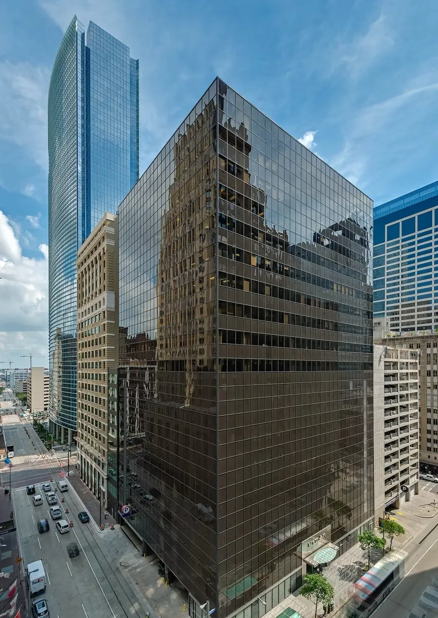 801 Travis, Innovation Tower, in Downtown Houston: a dark glass office tower on a street corner with a taller blue glass tower behind it